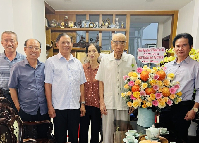 Ông Nguyễn Văn Tiến (thứ 3 bên trái) dẫn đoàn tặng hoa chúc mừng ông Nguyễn Kỳ Cẩm, 96 tuổi với 75 năm tuổi Đảng