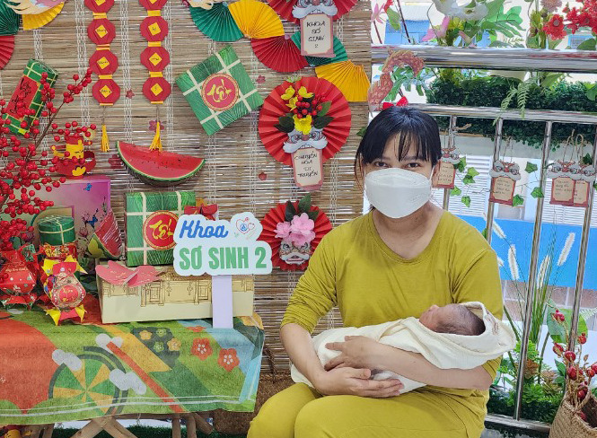 Bé trai được mẹ bế chụp hình bên tiểu cảnh Tết trước khi rời Bệnh viện Nhi đồng 1, ngày 18/2