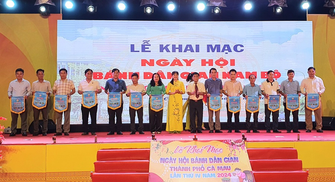 Các đơn vị tham gia Ngày hội bánh dân gian Nam Bộ TP. Cà Mau lần thứ IV năm 2024 nhận cờ lưu niệm của Ban Tổ chức