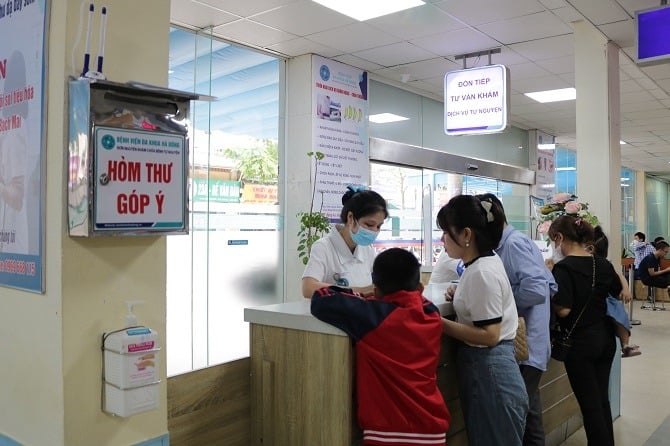 Nhân viên y tế tiếp đón và hướng dẫn người bệnh đăng ký khám bệnh tại Bệnh viện đa khoa Hà Đông