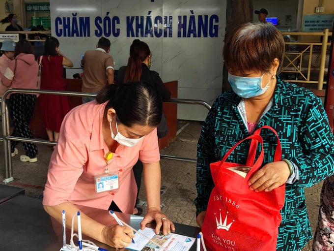 Nhân viên chăm sóc khách hàng ghi thông tin giúp người cao tuổi