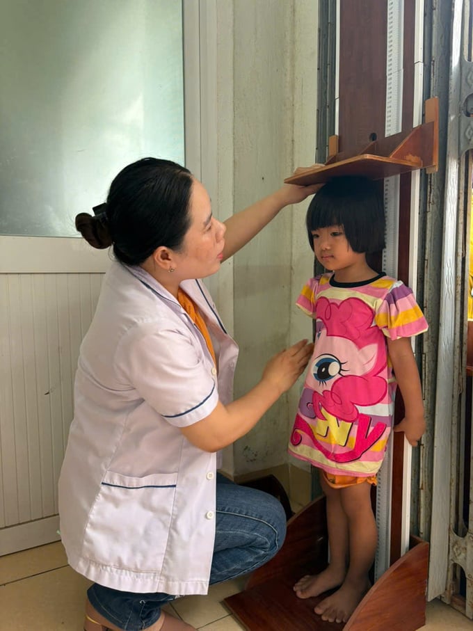 Đoàn cán bộ điều tra của Trung tâm Kiểm soát bệnh tật tỉnh cân đo trẻ tại Trạm Y tế xã Phước Hoà, huyện Tuy Phước (Ảnh: Thu Phương)