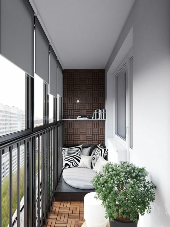 terrasse au sol en terre cuite avec un mur recouvert de panneau en bois dans les mêmes nuances, idee amenagement terrasse, matelas en simili cuir noir posé dans l'un des bouts, grands coussins aux prints zèbre, petits coussins blancs