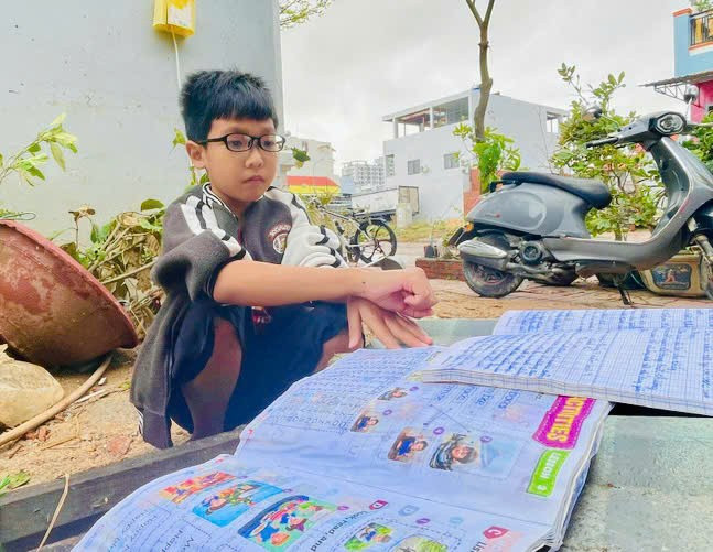 Sách vở của em Ngô Tấn Phú-học sinh Trường Tiểu học số 1 Nhơn Bình bị ướt sau trận lũ (Ảnh: Trần Dung)