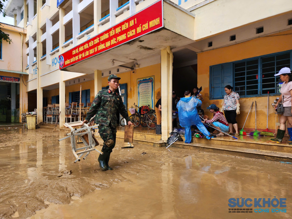 Các chiên sĩ bộ đội cùng các giáo viên trường Tiểu Học Diên An 1 dọn dẹp bùn đất (Ảnh: Thanh Huy)